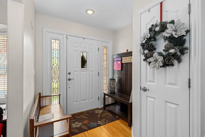 Entryway featuring a paneled front door with decorative glass inserts, sidelight windows, recessed lighting, and wood-finish flooring