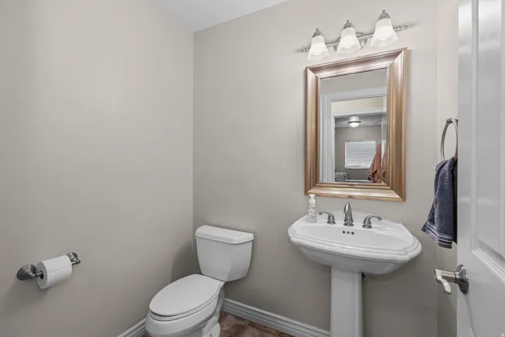 Pedestal sink with chrome-finish faucet, framed mirror, and three-light vanity fixture