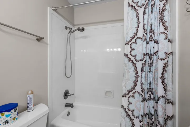 White bathtub and shower combination with a brushed nickel showerhead and faucet