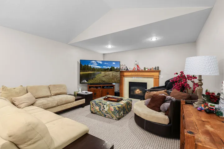 Inviting living area featuring a fireplace with a wood mantle and tile surround, recessed lighting, and neutral carpeting