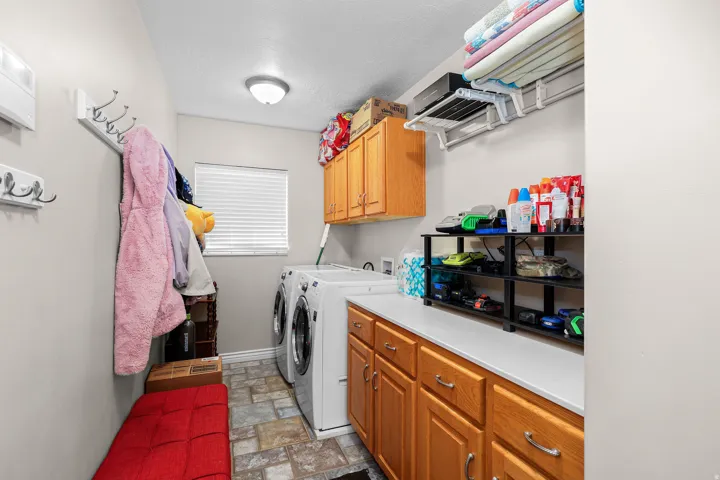 Functional laundry area featuring neutral wall tones, durable tile-finish flooring, and a window with blinds