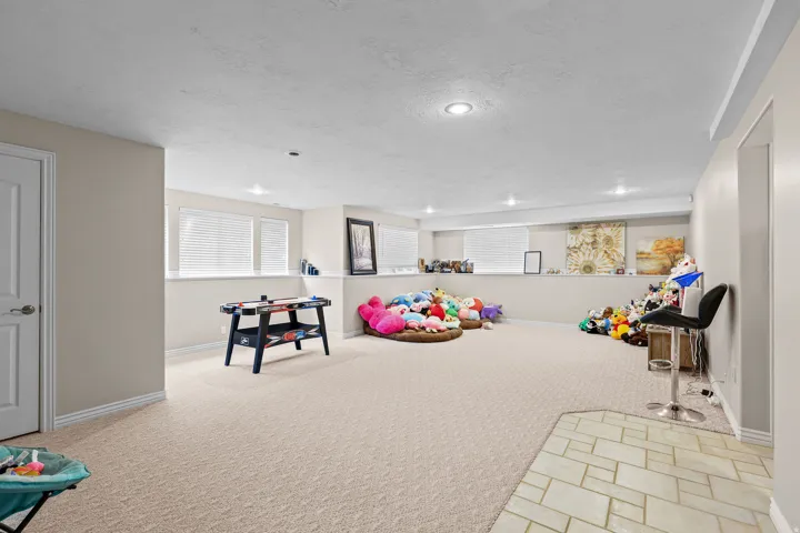 Spacious lower-level room featuring recessed lighting, light-toned wall paint, and windows with horizontal blinds
