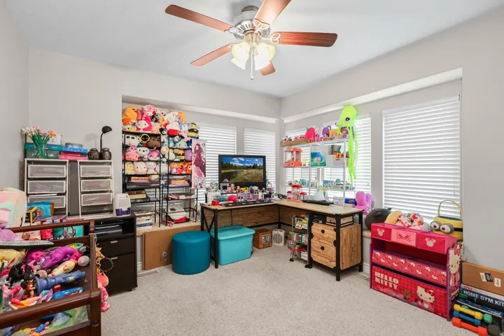 Carpeted room featuring multiple windows with blinds, a ceiling fan with integrated lighting, and light gray wall paint