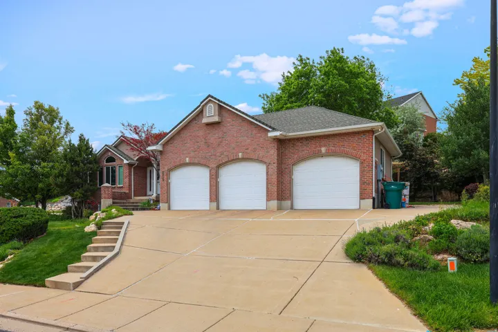 Brick exterior residence featuring a three-car garage with arched entrances and white garage doors