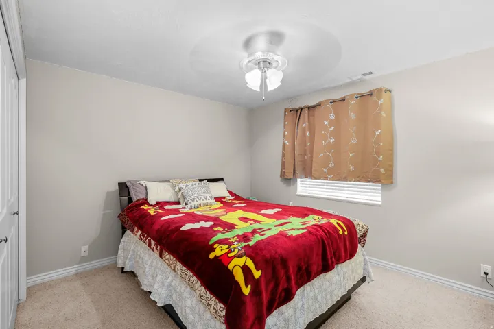 Carpeted room with a ceiling fan, baseboard molding, and a window featuring horizontal blinds