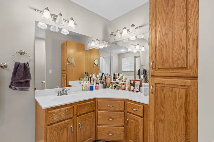 Bathroom vanity featuring an integrated sink, white countertop, and light wood cabinetry