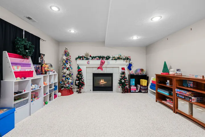 Carpeted room featuring a fireplace with a white mantel and tile surround, recessed lighting, and light-toned walls