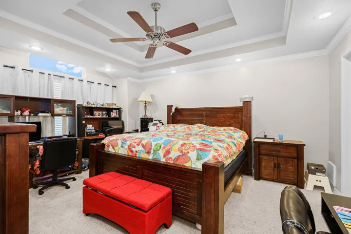 Spacious sleeping area featuring a tray ceiling with a ceiling fan, recessed lighting, and crown molding
