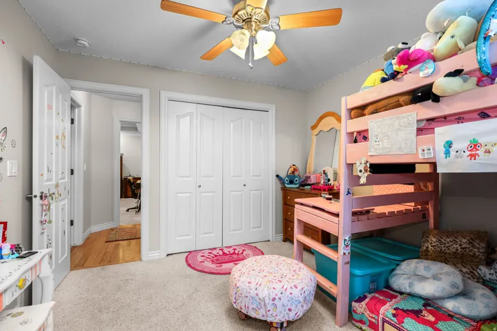 Carpeted room with a ceiling fan light fixture, white bi-fold closet doors, and a wood-finish interior door