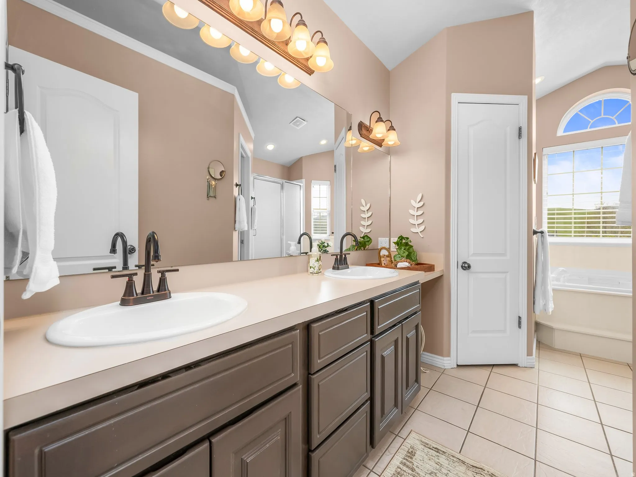 Double vanity with integrated sinks and bronze-finish faucets set against a full-width mirror
