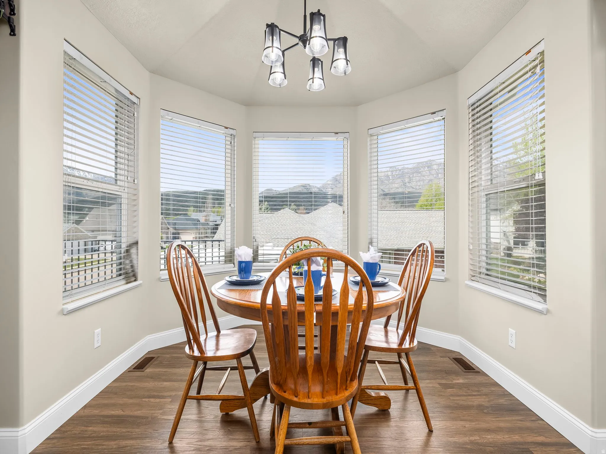Bay window dining area featuring wood-finish flooring, light neutral wall paint, and a contemporary multi-light fixture