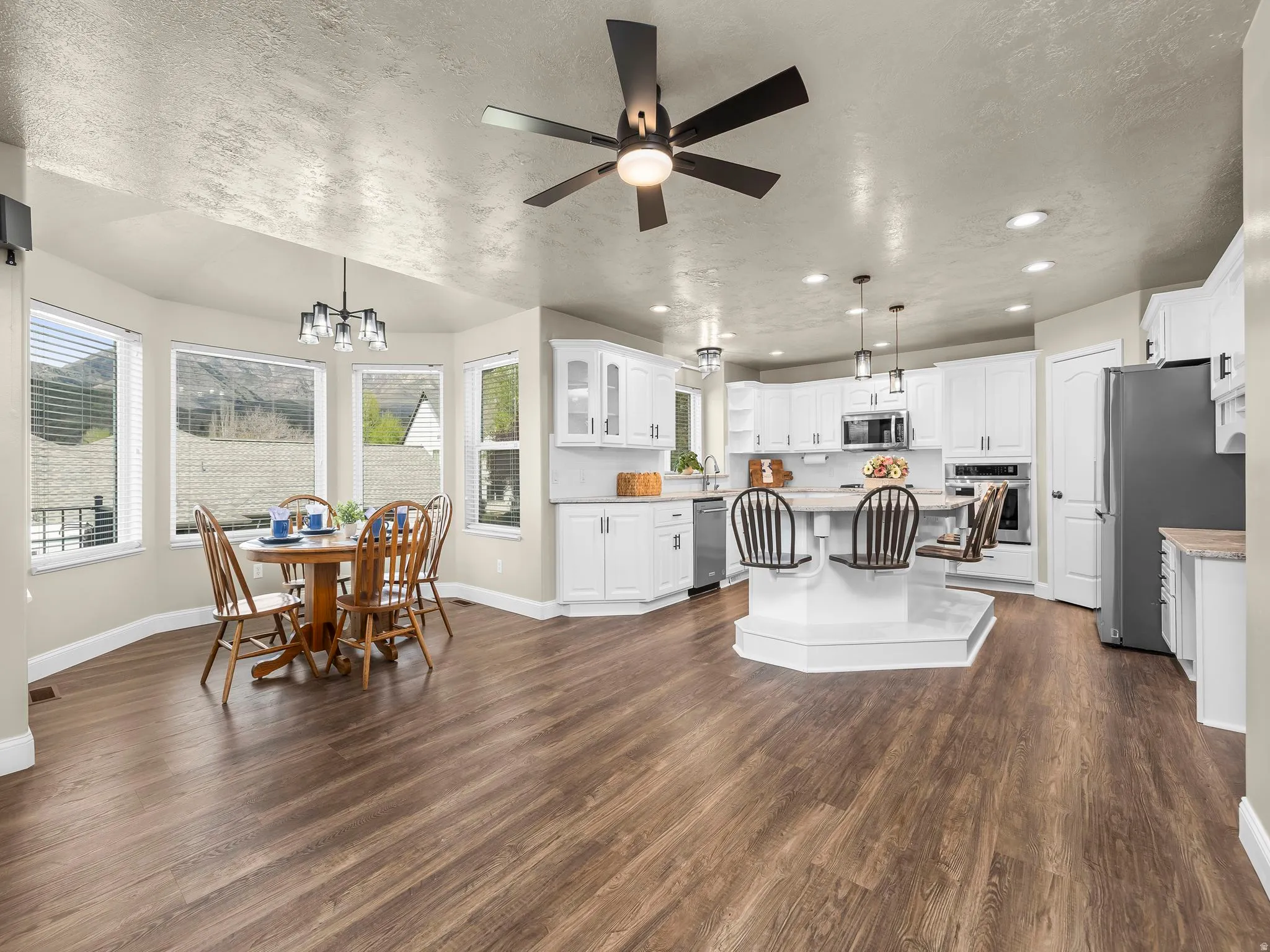 Open-concept living space featuring wood-finish flooring, a contemporary ceiling fan, and recessed lighting