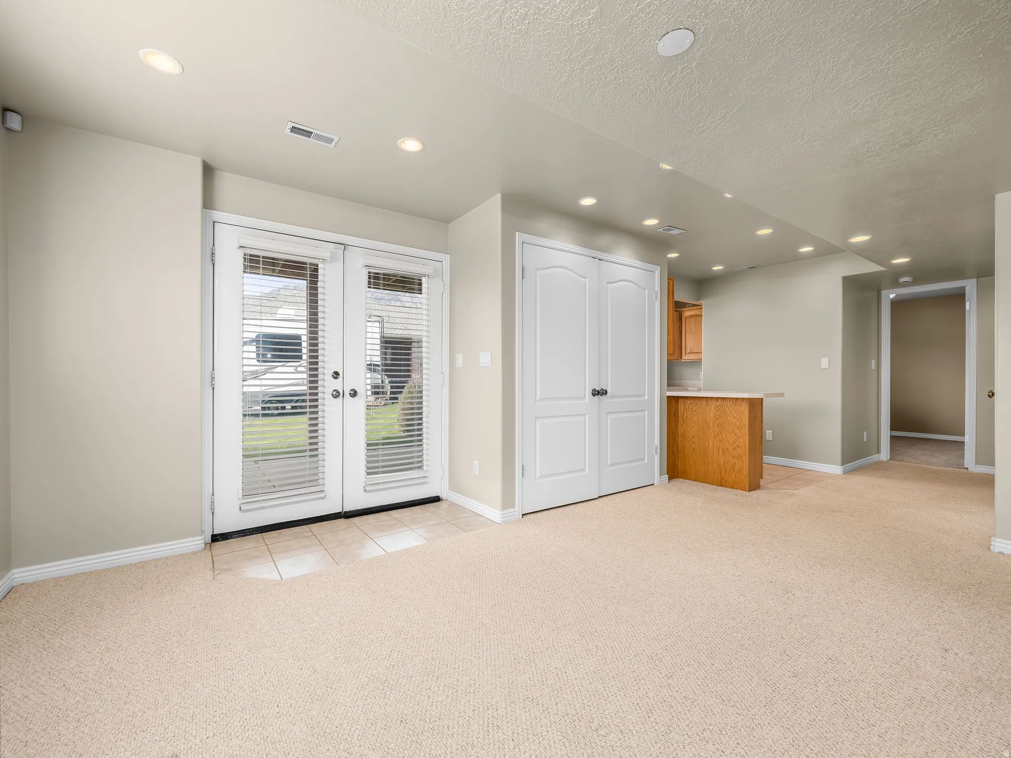 Spacious room featuring neutral carpeting and recessed lighting