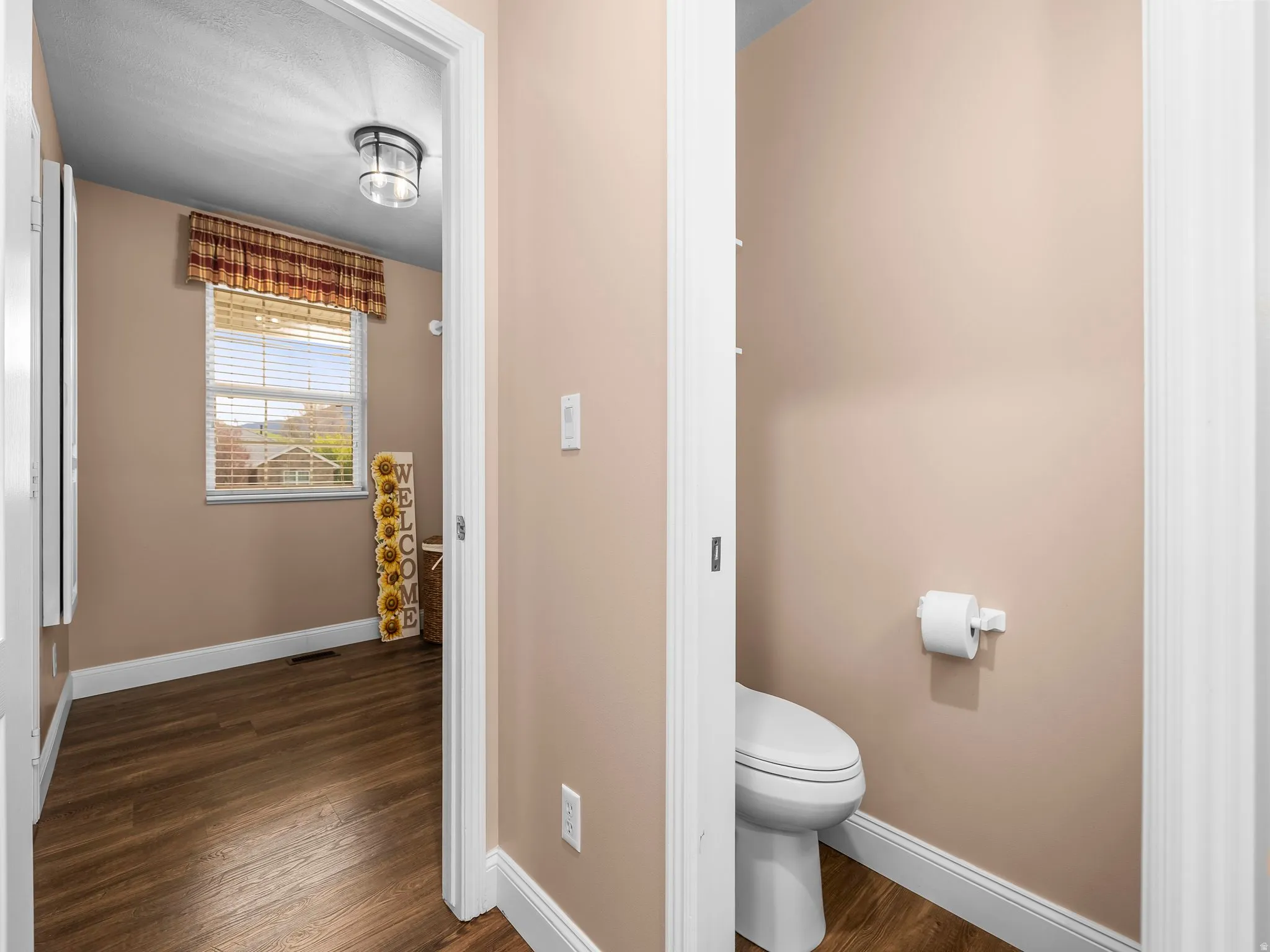 Interior hallway featuring wood-finish flooring, a window with horizontal blinds, and a flush-mount ceiling light