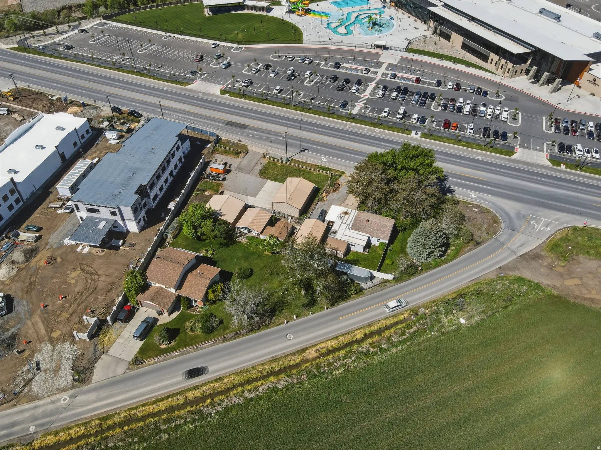 Expansive aerial perspective showcasing a residential property with a driveway and surrounding green spaces