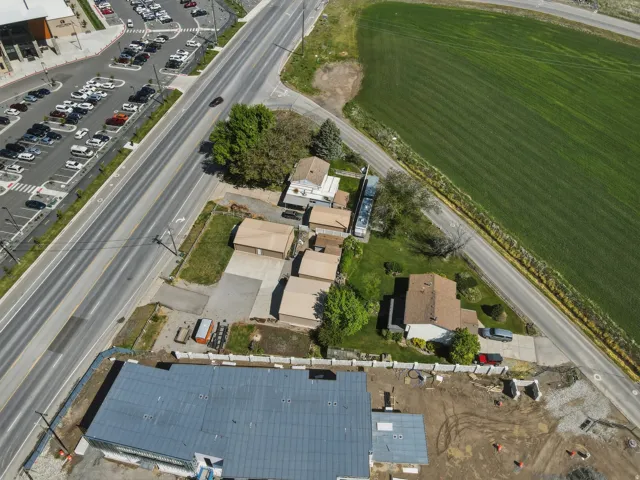 Expansive property featuring a single-story residence with a brown shingle roof, accompanied by multiple detached garages