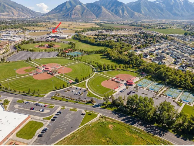 Aerial perspective showcasing a large community park with multiple baseball fields, tennis courts, and ample parking