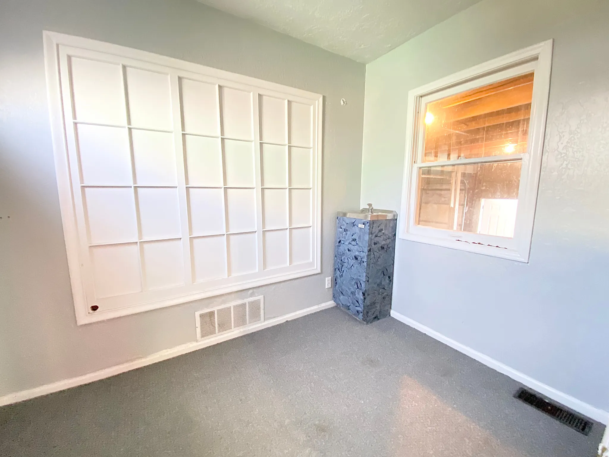 Windowed interior space featuring light gray wall paint and gray flooring