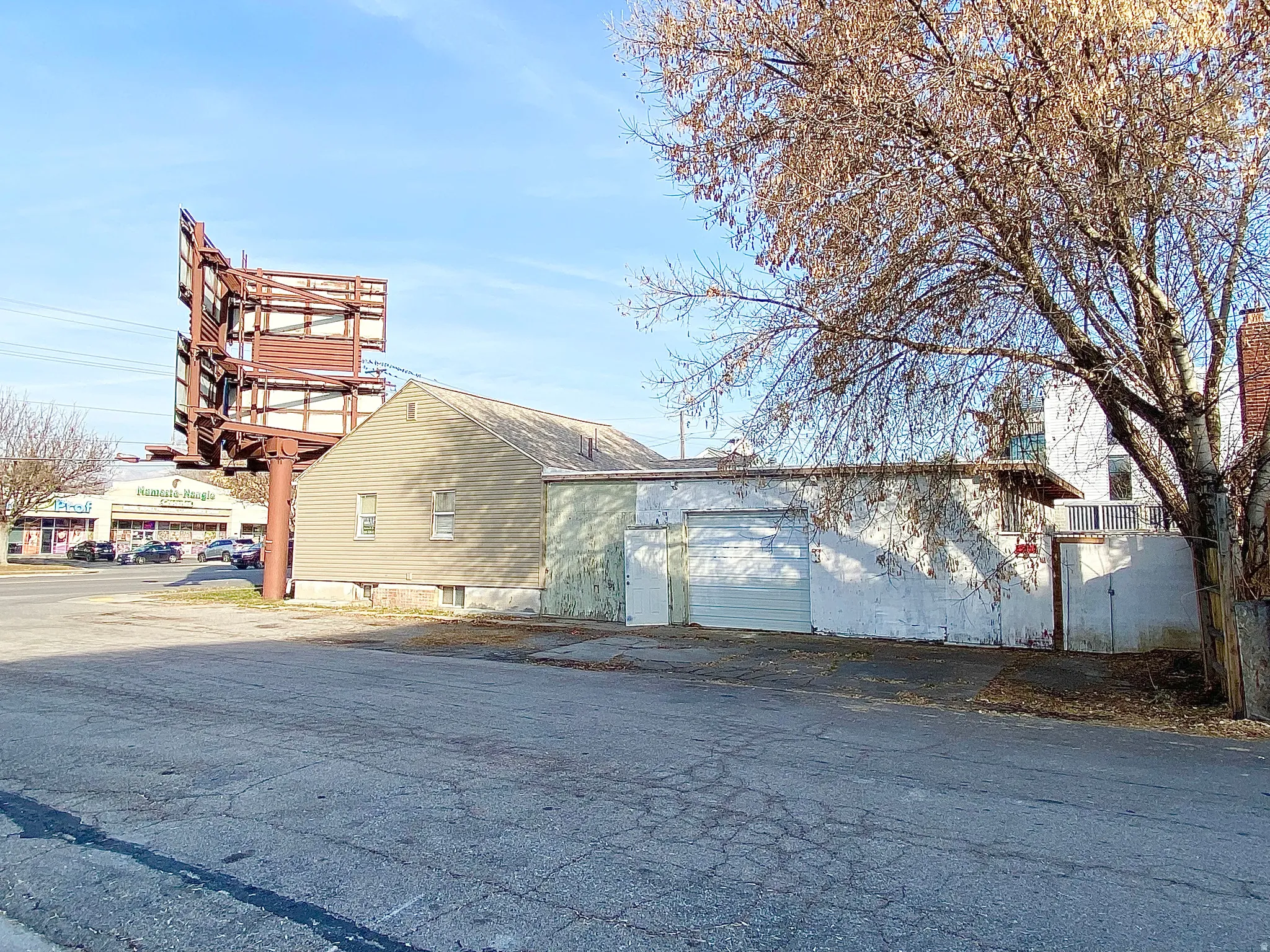 Commercial building featuring an exposed aggregate driveway, two garage doors, and a billboard structure