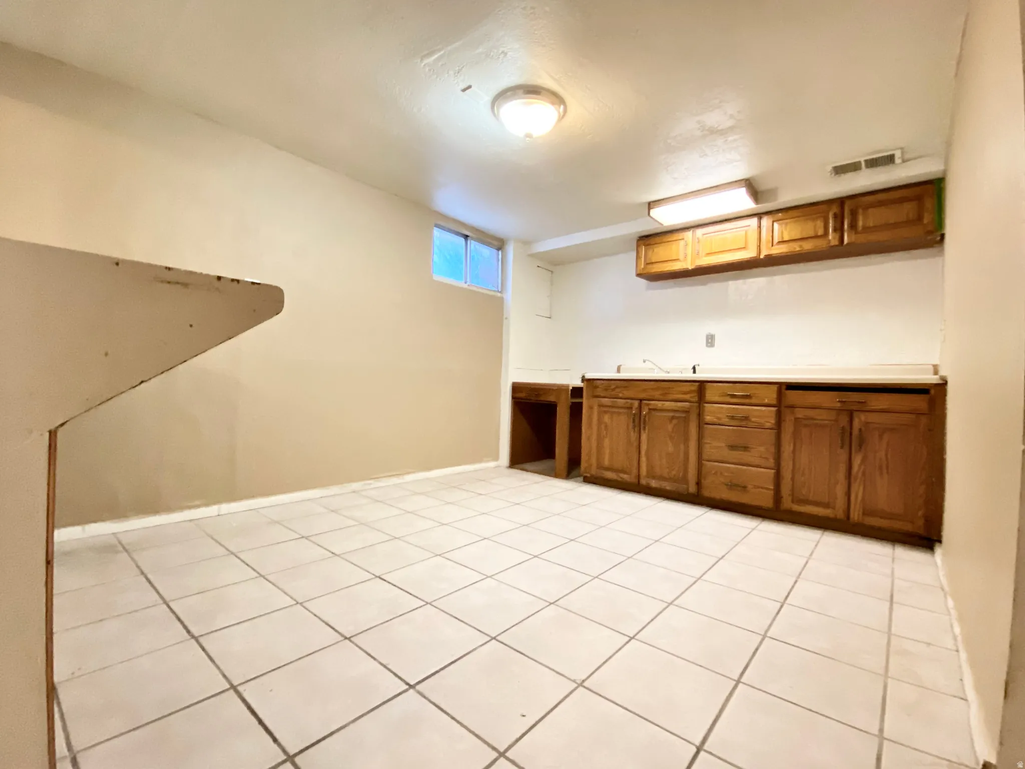 Open concept area with a light tile floor, wood-finish cabinetry, and a countertop space
