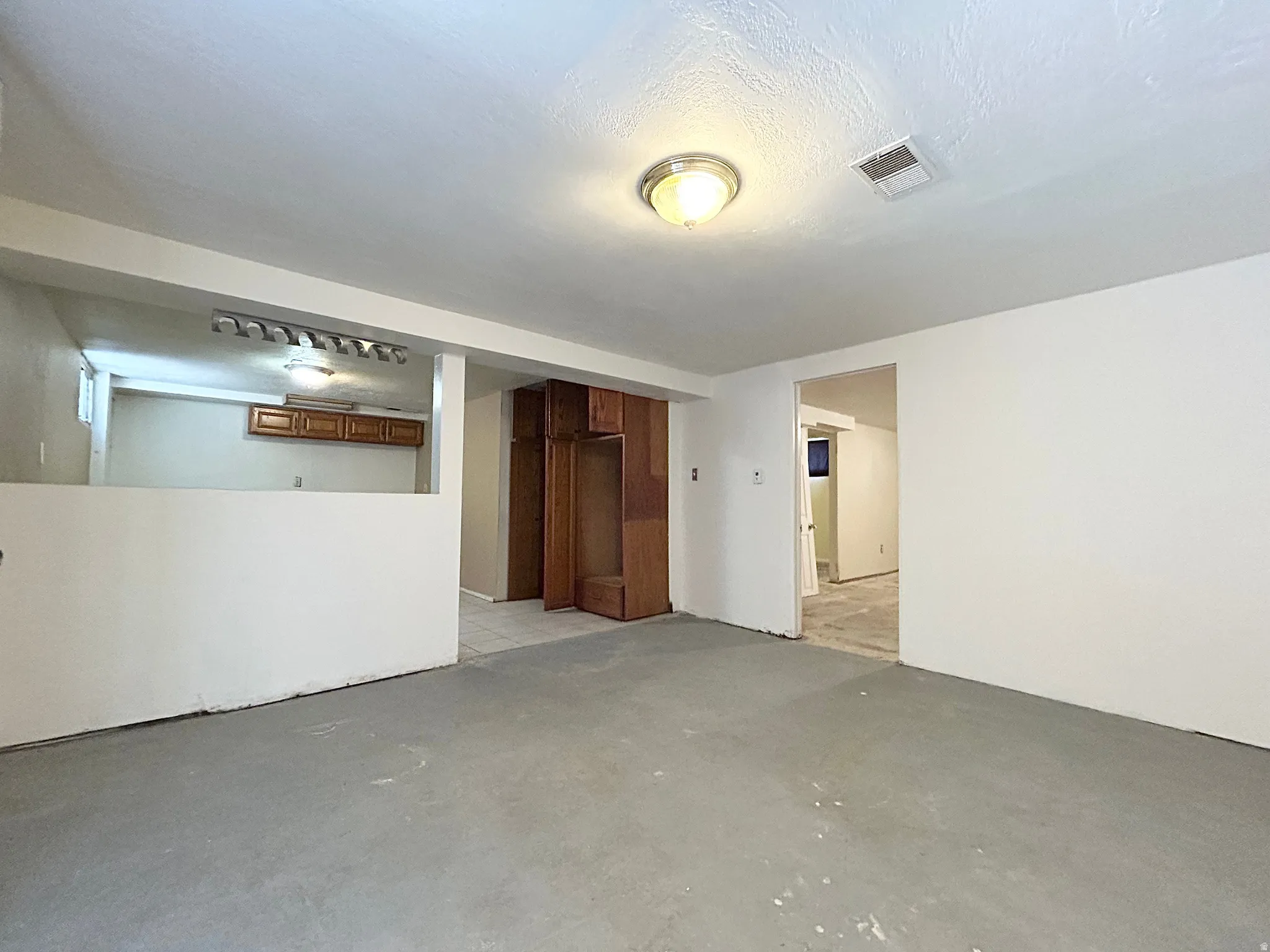 Open concept room featuring a half-wall partition, built-in wooden cabinetry, recessed lighting, and a neutral color palette