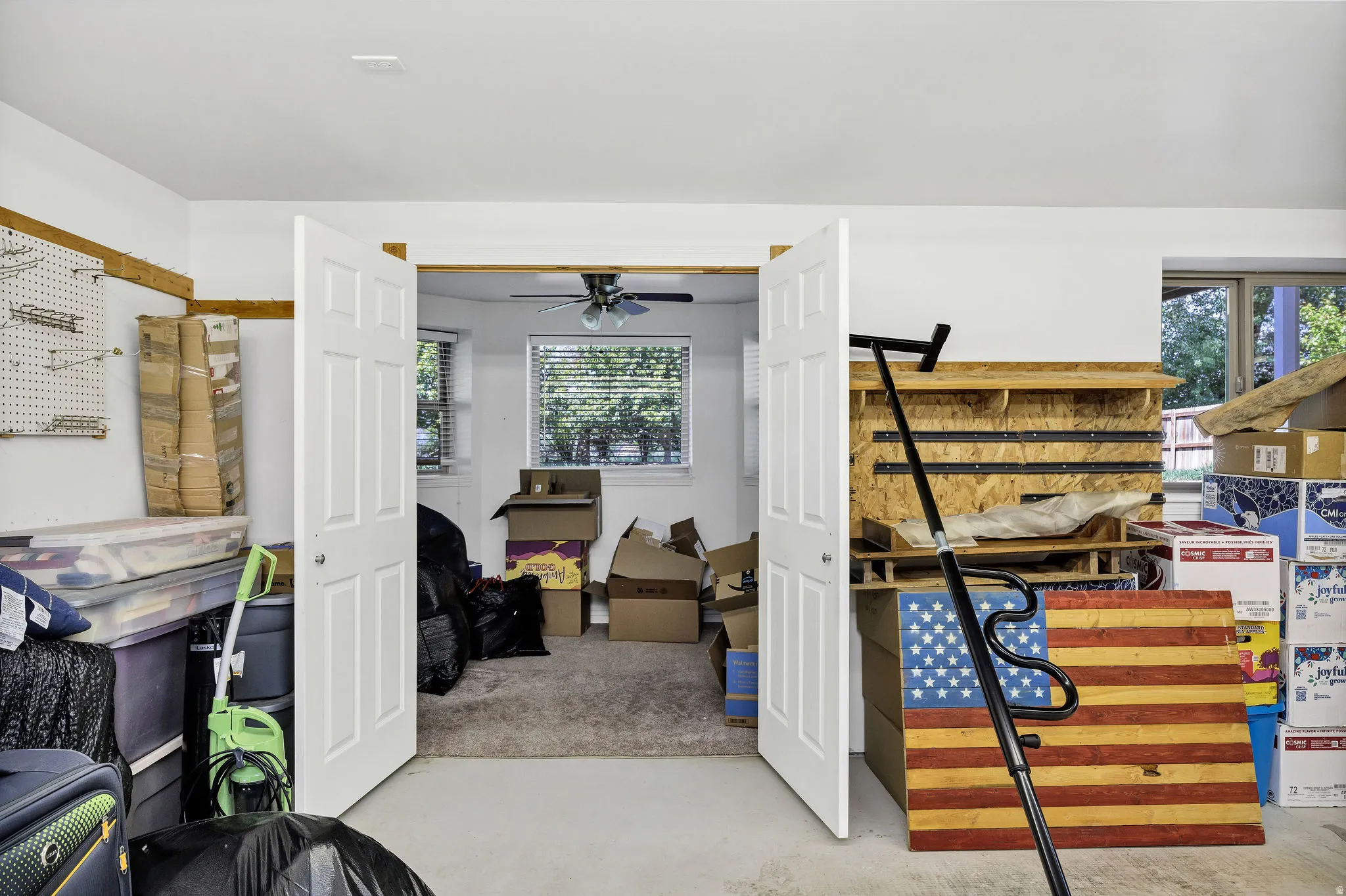 Carpeted room featuring a ceiling fan, two windows with blinds, and white double doors