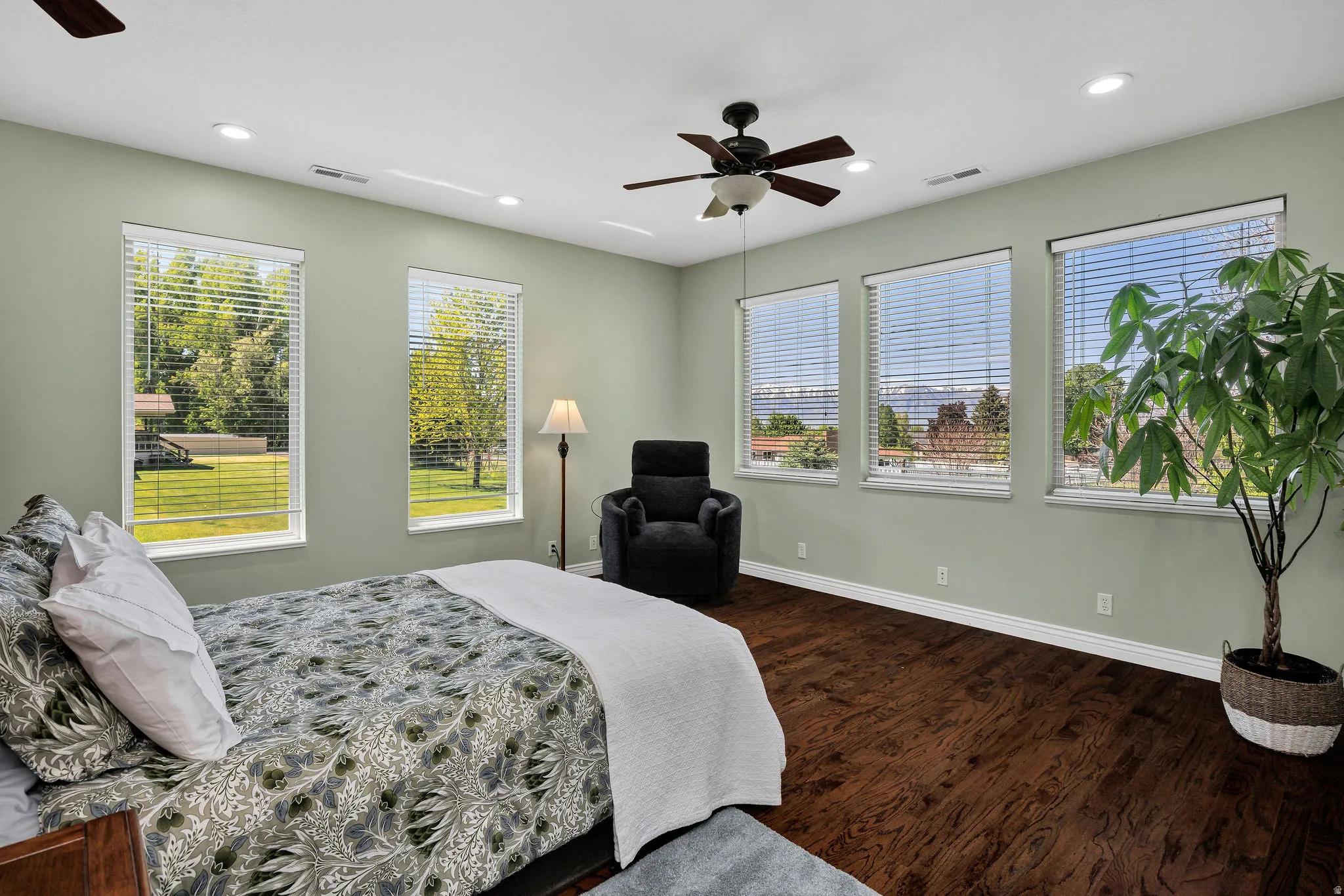 Spacious room featuring rich wood-finish flooring, light-toned walls, and five windows with slatted blinds