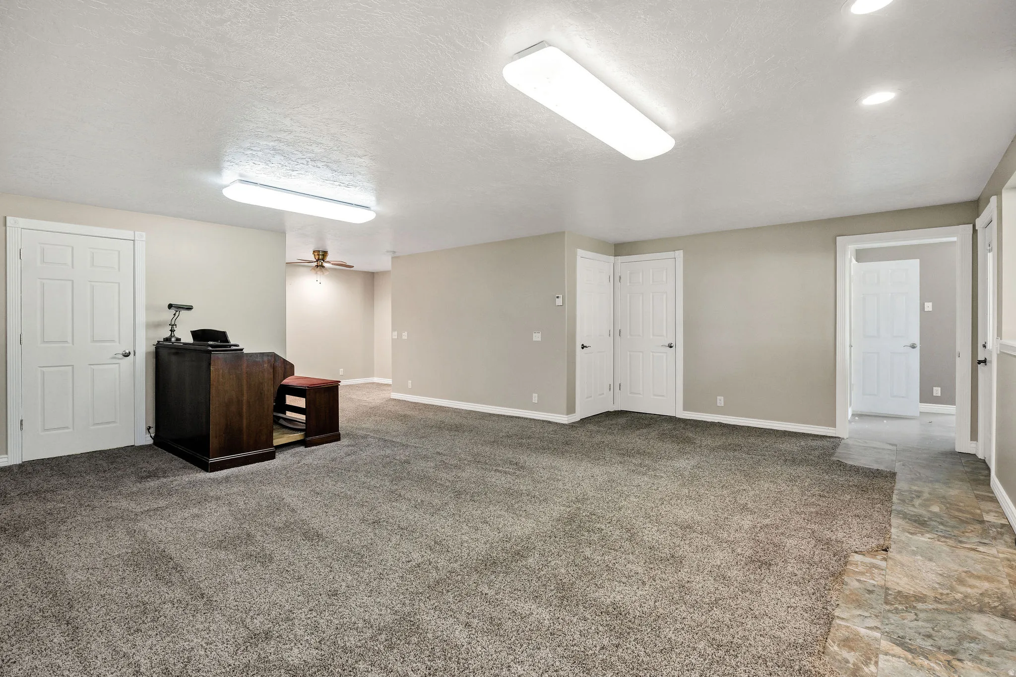 Spacious room with plush gray carpeting, neutral-toned walls, and white trim