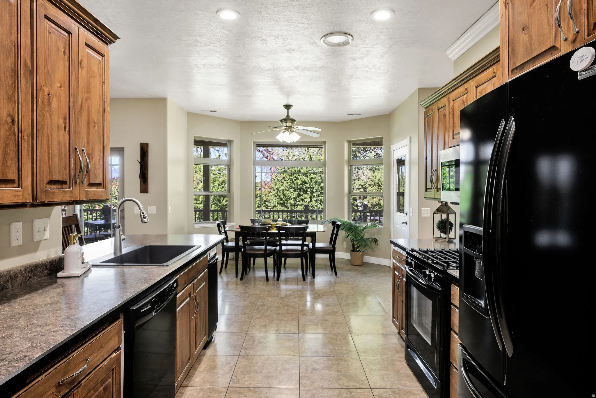 Kitchen featuring wood-finish cabinetry, black appliances, and a double basin sink