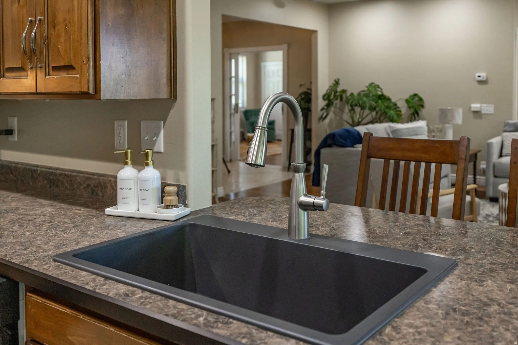 Kitchen sink with a contemporary pull-down faucet and a dark composite basin, set into a textured countertop