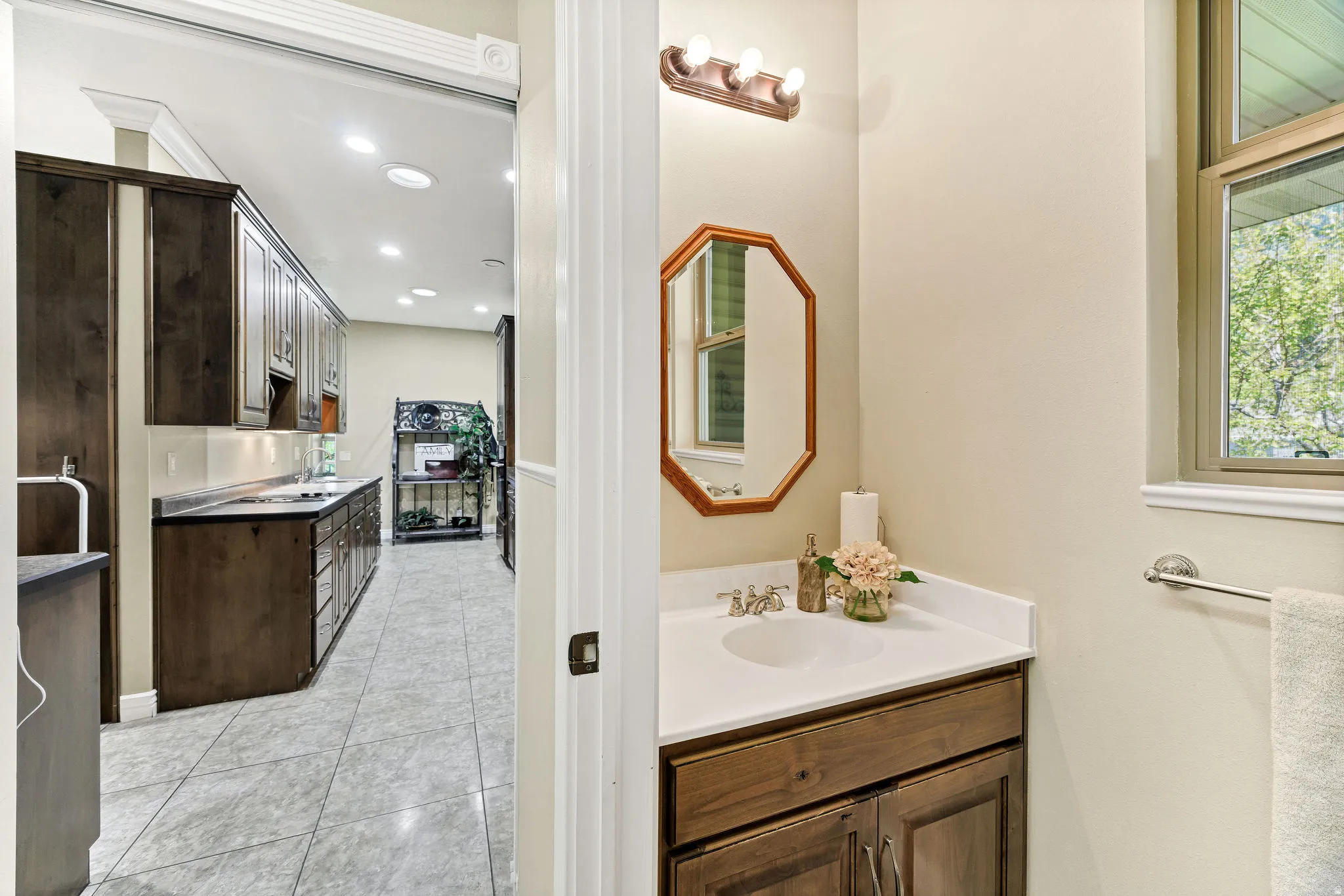 Bathroom vanity featuring a single basin sink, white countertop, wood-finish cabinet, and an octagonal mirror