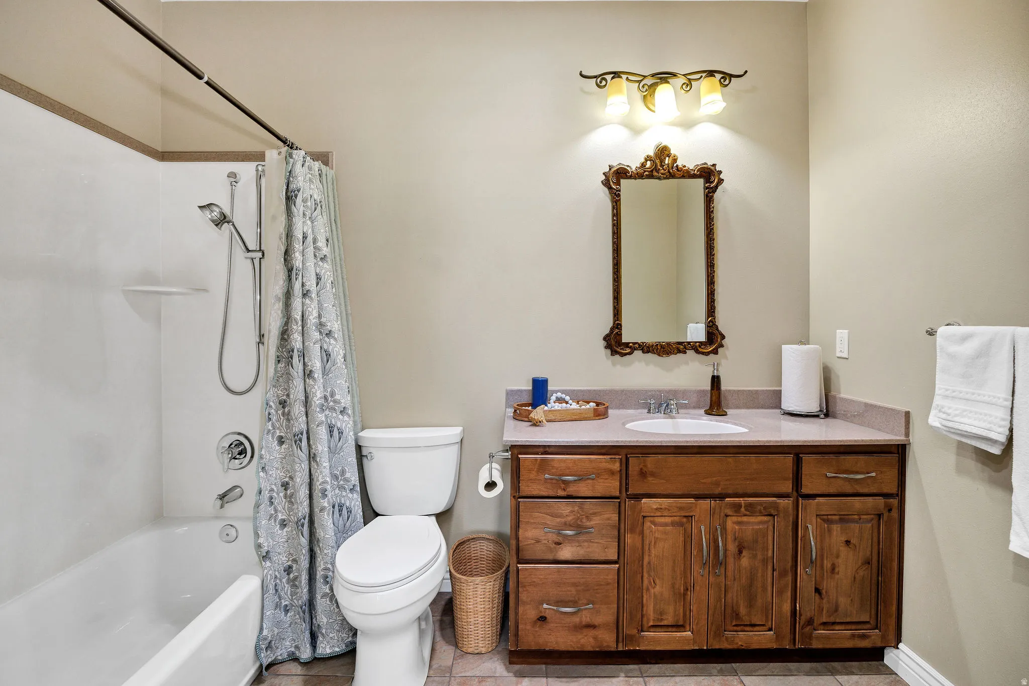 Full en suite bathroom featuring a wood-finish vanity with a single basin sink, a framed mirror, a tub/shower combination, and a commode
