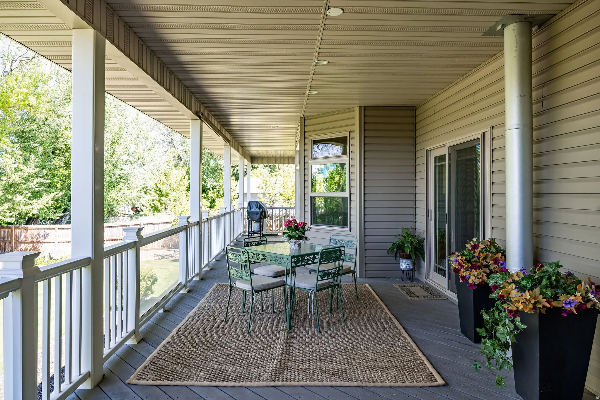 Expansive covered porch featuring a composite deck, white baluster railing, recessed lighting, and direct access through sliding glass doors