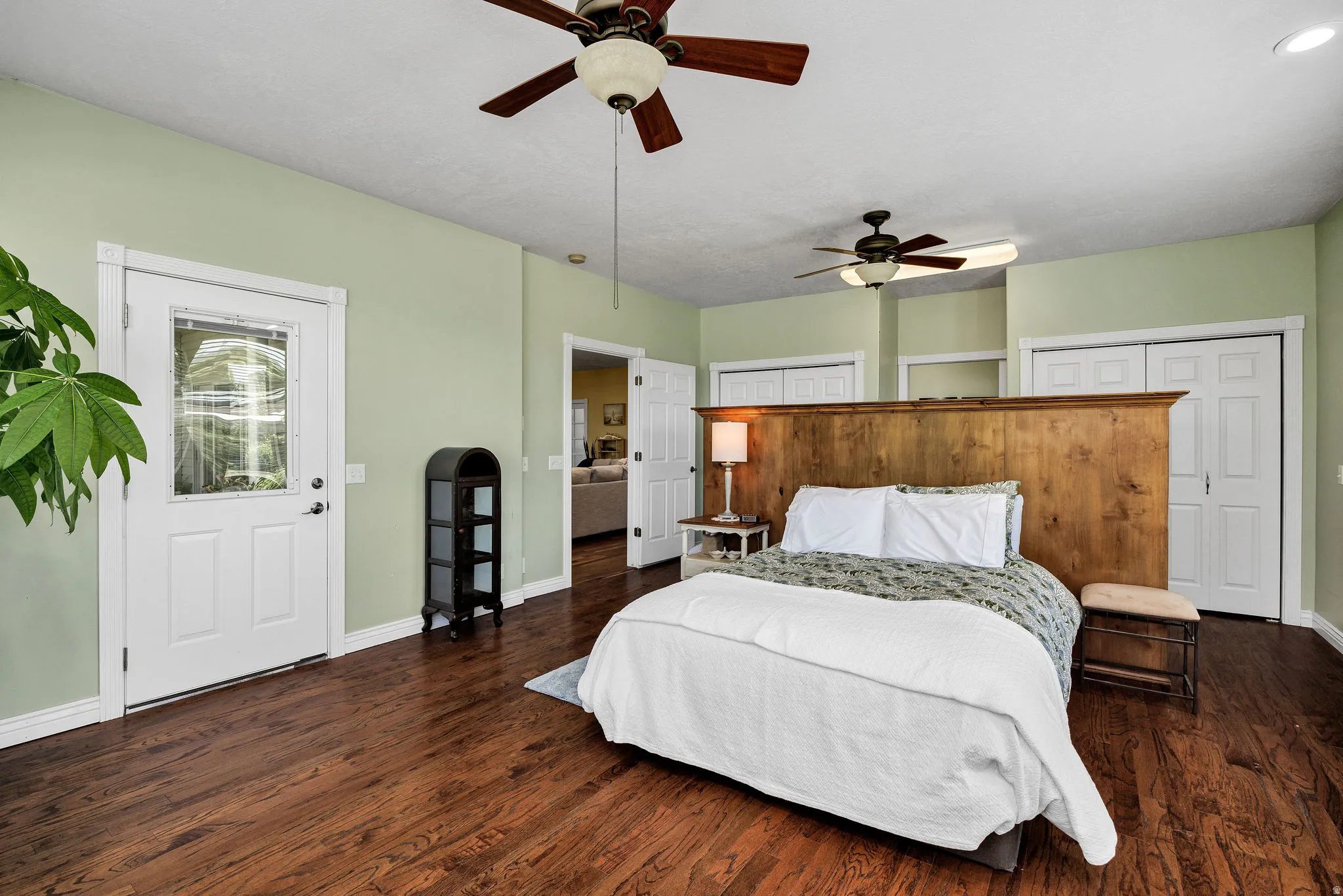 Spacious room featuring wood-finish flooring, light green walls, and a white door with a clear glass insert