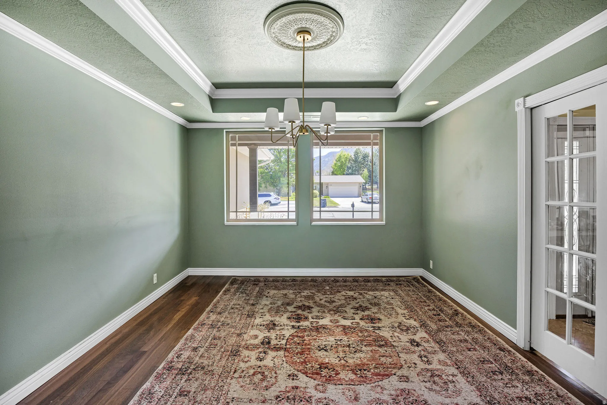 Formal room featuring a tray ceiling with recessed lighting and a central chandelier