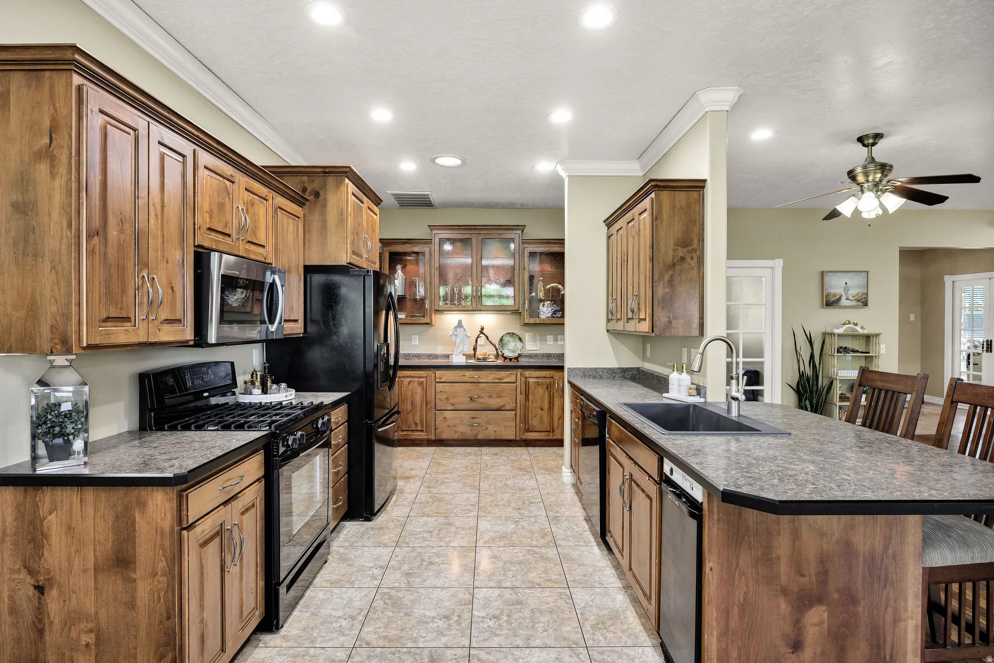 Kitchen featuring ample wood cabinetry, tile flooring, recessed lighting, and a kitchen island with a built-in sink and seating