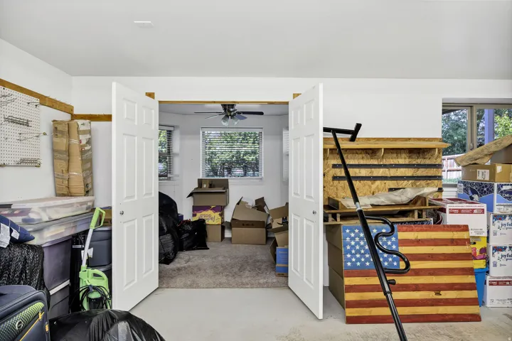Carpeted room featuring a ceiling fan, two windows with blinds, and white double doors