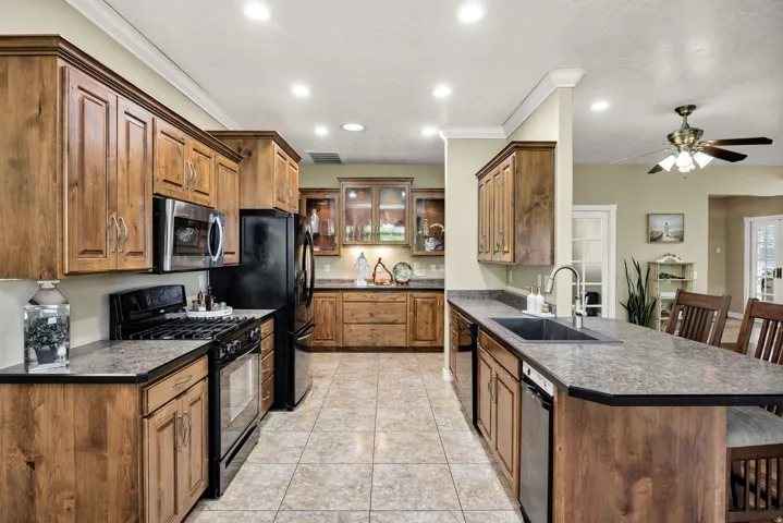 Kitchen featuring ample wood cabinetry, tile flooring, recessed lighting, and a kitchen island with a built-in sink and seating