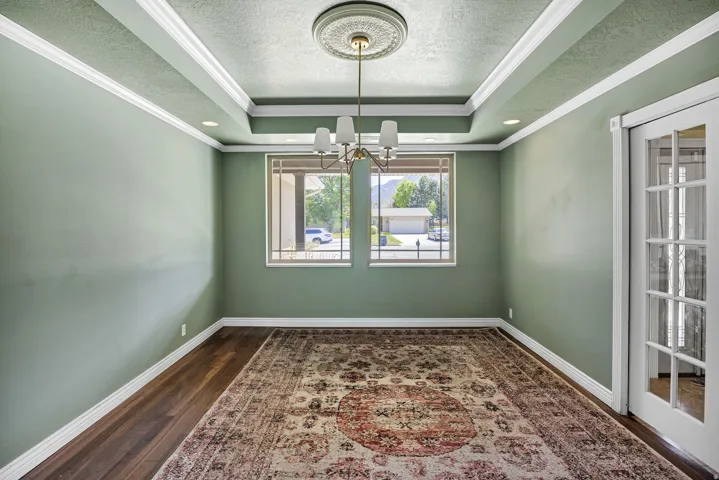 Formal room featuring a tray ceiling with recessed lighting and a central chandelier