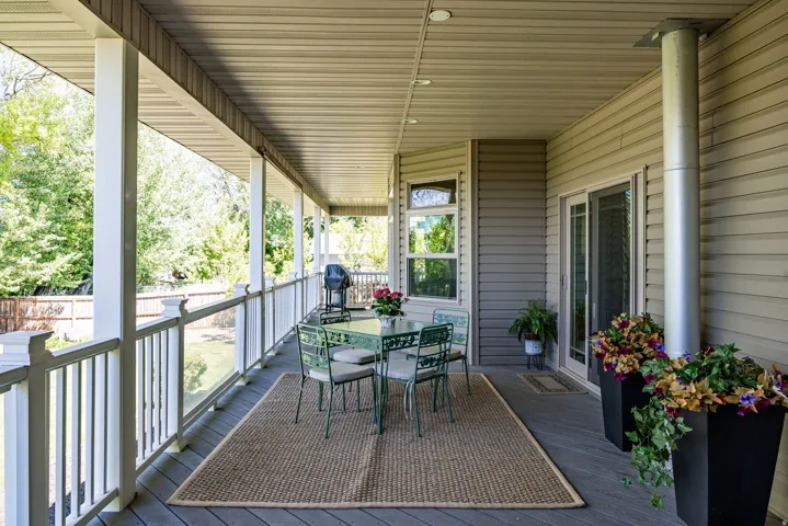Expansive covered porch featuring a composite deck, white baluster railing, recessed lighting, and direct access through sliding glass doors