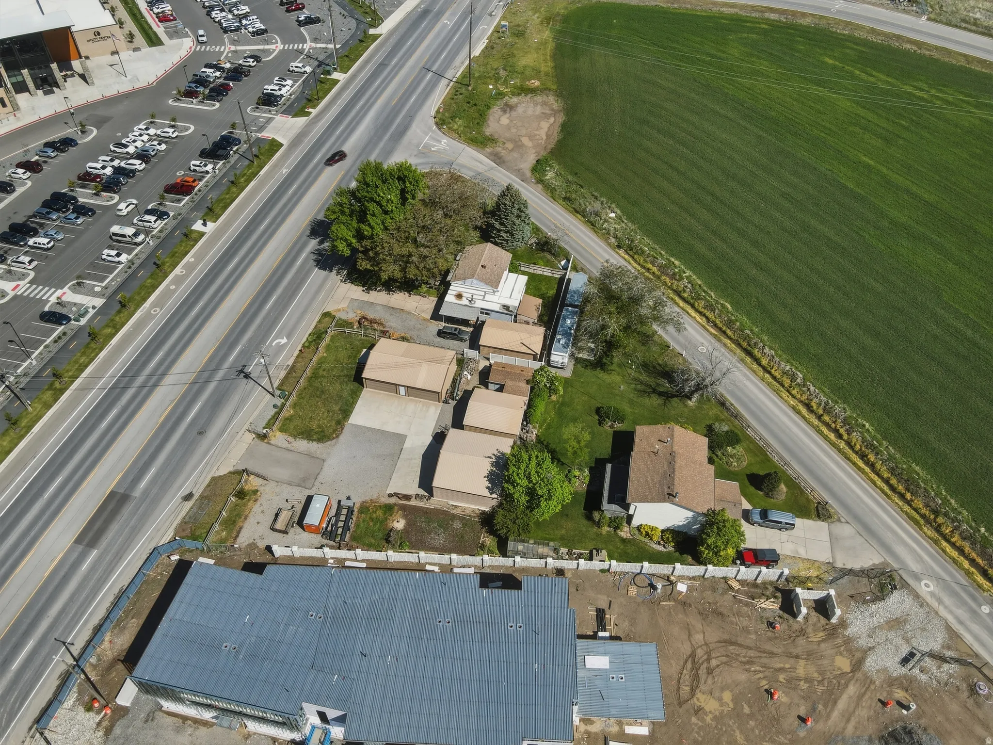 Expansive property featuring a single-story residence with a brown shingle roof, accompanied by multiple detached garages