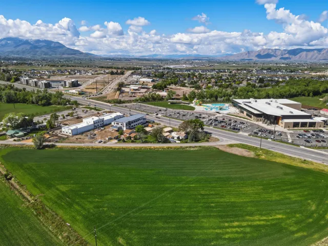 Expansive green field with surrounding residential areas and distant mountains