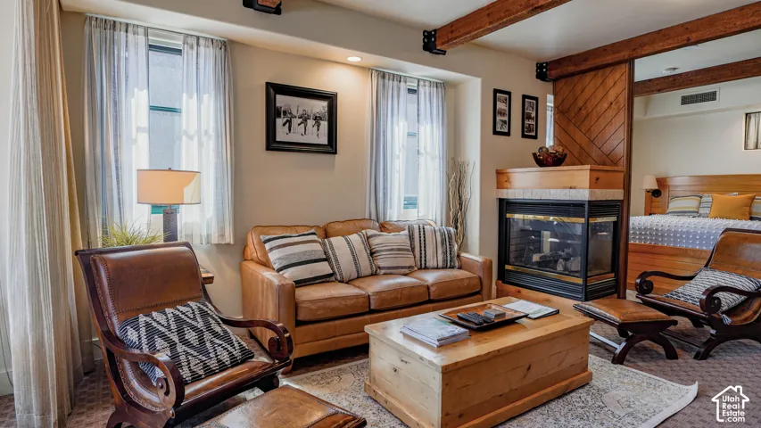 Living area featuring exposed wood beams, a built-in fireplace with a wood mantle, and a sliding wood barn door