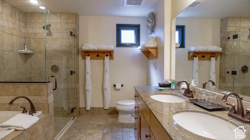 Bathroom featuring a dual vanity with a stone countertop, bronze-finish fixtures, and integrated sinks