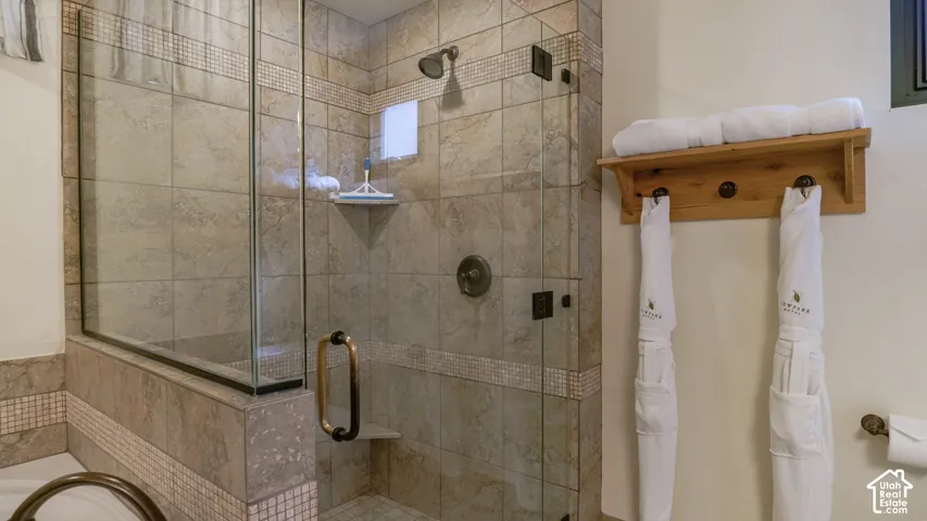 Glass-enclosed shower featuring natural-toned tile work with mosaic accents