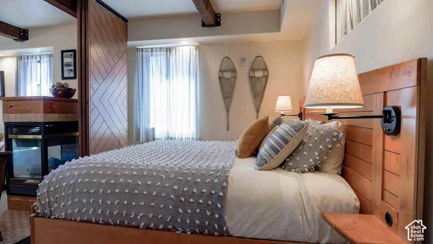 Warm bedroom featuring a wood-panel accent wall and two windows with sheer privacy coverings