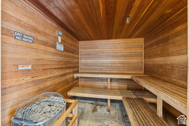 Wood-paneled dry sauna featuring slatted benches, a rock heater, and integrated overhead lighting