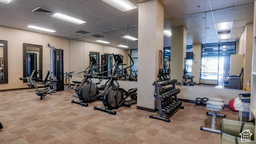 Fitness center featuring patterned carpet flooring, full-length mirror walls, and recessed lighting