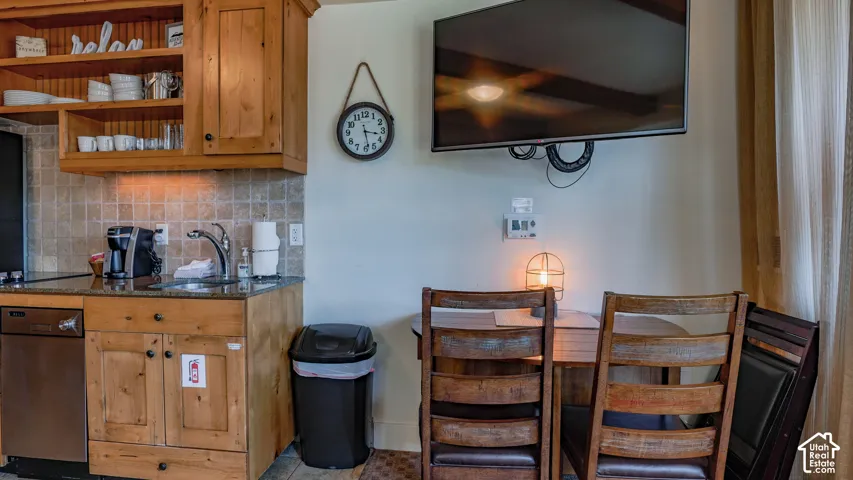 Compact kitchen area featuring wood cabinetry, granite-style countertops, and a tile backsplash