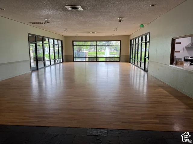 Spacious open-concept room featuring wide-plank wood-finish flooring and extensive window walls providing ample natural illumination